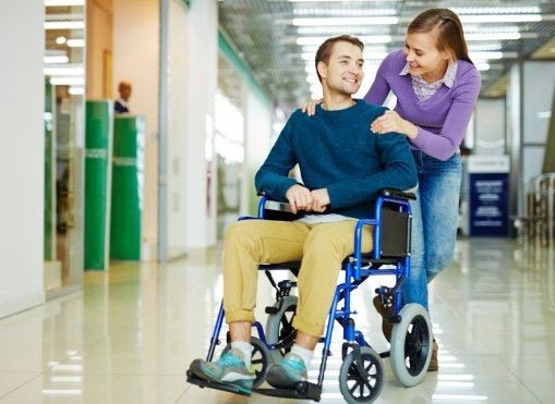 Carer pushing a smiling man in a wheelchair