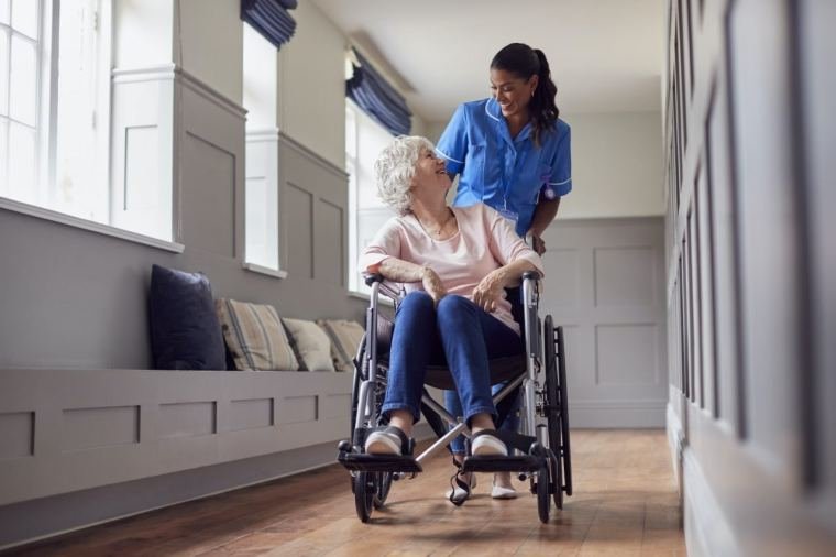 Care worker pushing a smiling senior woman in a wheelchair